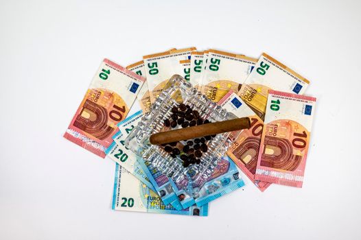 50 20 10 euro banknotes with ashtray and cigar on white background