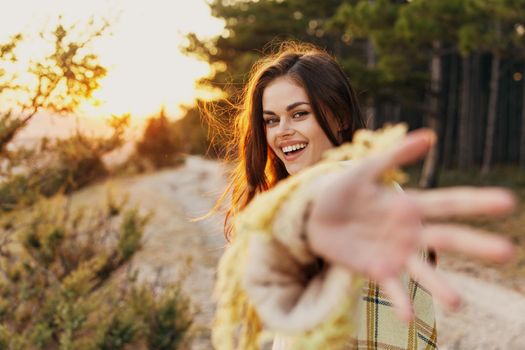 happy woman in nature shows her palm and laughs near coniferous trees. High quality photo