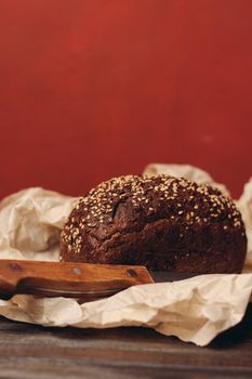 rye bread on paper packaging on a red background and a wooden table with a sharp knife. High quality photo