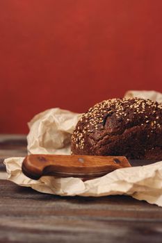 rye bread on paper packaging on a red background and a wooden table with a sharp knife. High quality photo