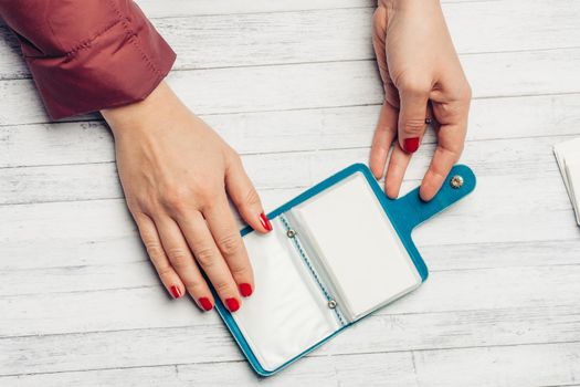 blue business card holder in female hands on a wooden table top view. High quality photo
