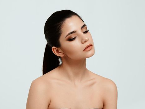young woman with bare shoulders face makeup and closed eyes. High quality photo