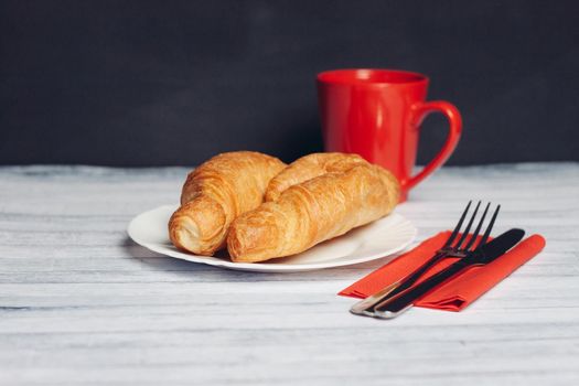 croissants on a plate a cup of coffee wooden table dessert. High quality photo