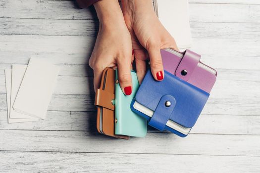 multicolored business card holders in female hands and a pack of white paper on a wooden background. High quality photo