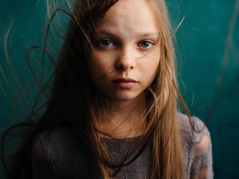 A girl with shaggy hair on a turquoise background and a gray sundress. High quality photo