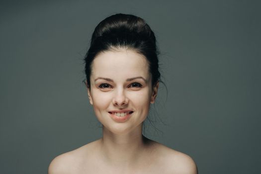 beautiful woman smiling on gray background naked shoulders cropped view hairstyle. High quality photo