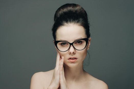 portrait of beautiful brunette with glasses naked shoulders gesturing with hands. High quality photo