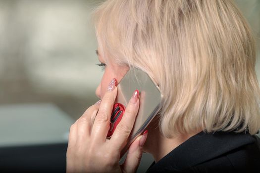 A woman director working in an office is sitting at a table, talking on the phone, checking documents. Close-up.