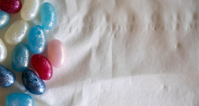 Colorful candy beans placed on top of a white background crumpled paper
