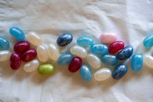 Colorful candy beans placed on top of a white background crumpled paper
