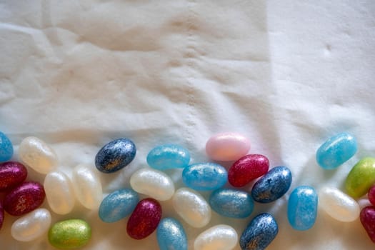 Colorful candy beans placed on top of a white background crumpled paper