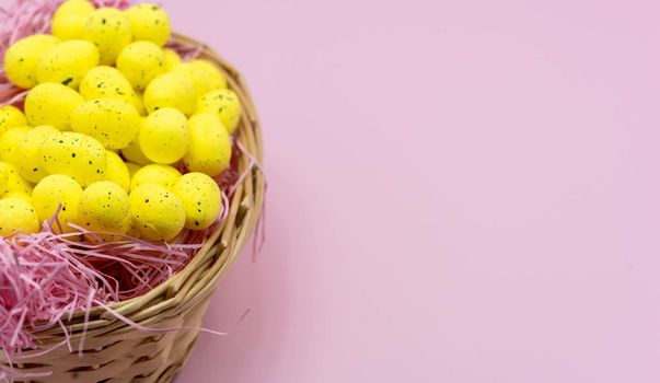 Yellow Easter Egg with freckles pattern inside a basket on Pink Background