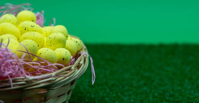 Yellow Easter Egg with freckles pattern inside a basket on top of grass