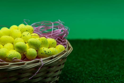 Yellow Easter Egg with freckles pattern inside a basket on top of grass