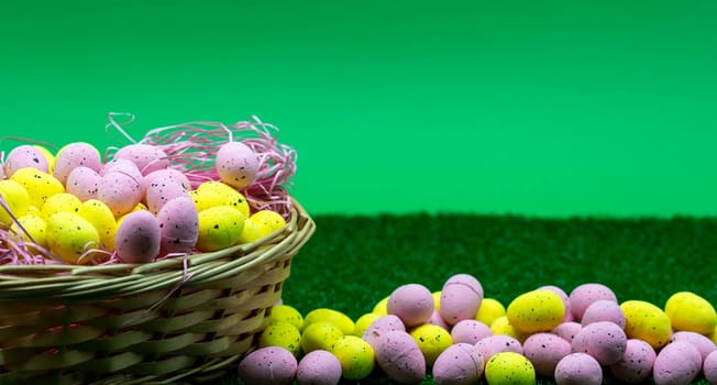Colorful Yellow and Pink easter egg with freckle patterns in a basket with green background and grass