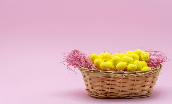 Yellow Easter Egg with freckles pattern inside a basket on Pink Background