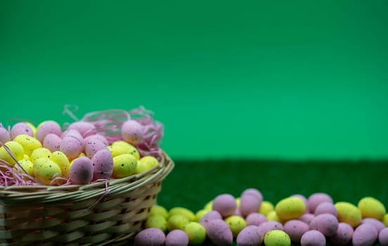 Colorful Yellow and Pink easter egg with freckle patterns in a basket with green background and grass