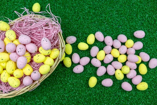 Colorful Yellow and Pink easter egg with freckle patterns inside a basket on grass