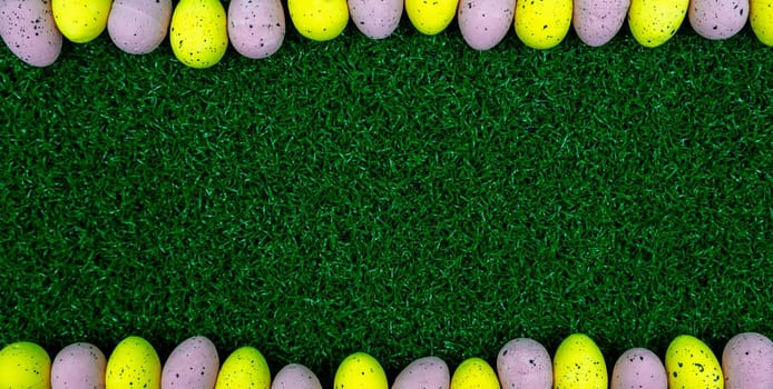 Colorful Yellow and Pink easter egg with freckle patterns on grass with copy space