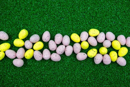 Colorful Yellow and Pink easter egg with freckle patterns on grass with copy space
