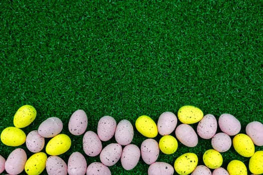 Colorful Yellow and Pink easter egg with freckle patterns on grass with copy space