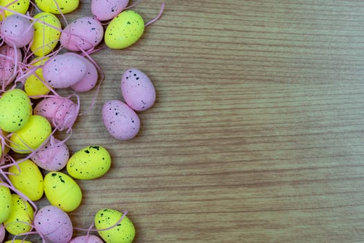Colorful Yellow and Pink easter egg with freckle patterns on wooden table with copy space