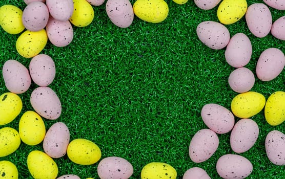 Colorful Yellow and Pink easter egg with freckle patterns on grass with copy space
