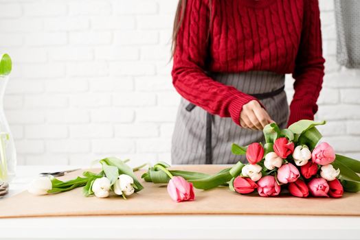 Valentine's Day and Women's Day. Small business. Woman florist making a bouquet of fresh colorful tulips