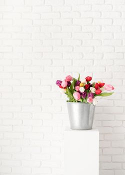Bucket of fresh tulip flowers over white brick wall background