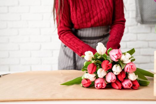 Valentine's Day and Women's Day. Small business. Woman florist making a bouquet of fresh colorful tulips