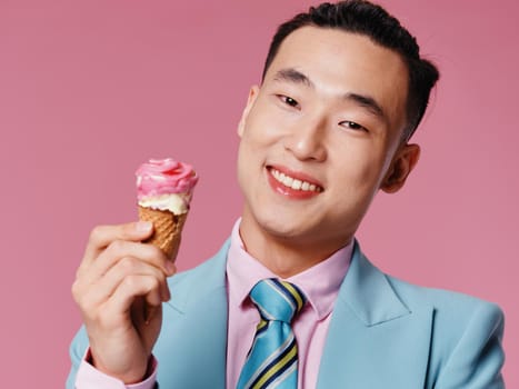Happy man with ice cream in a cone smiling on a pink background cropped view close-up. High quality photo