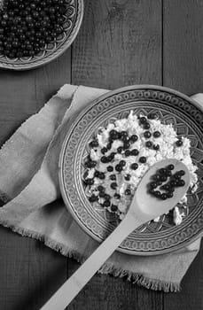 On the table in a ceramic plate delicious natural cottage cheese with red currant berries. close-up, top view. Copy space.