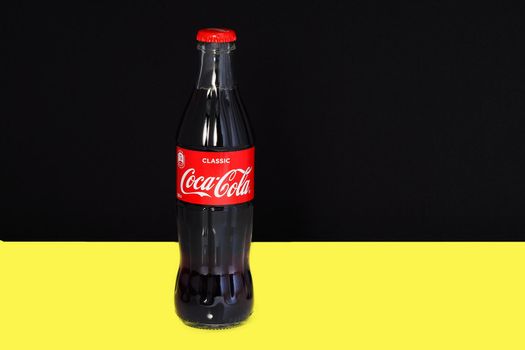 Non-alcoholic fizzy drink Coca Cola in a glass transparent bottle in isolation on a yellow background. Editorial image. High quality photo. Editorial image. Russia Nizhny Novgorod 22.02.2021