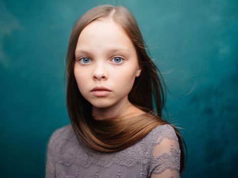 Portrait of a pretty girl in a gray dress and blonde hair on a turquoise background. High quality photo