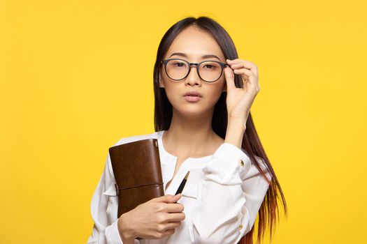 Business woman in glasses holding notepad in hands official yellow isolated background. High quality photo