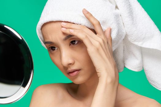 pretty asian woman looking in the mirror and touching her face close-up. High quality photo