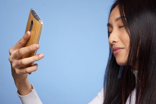 pretty brunette with phone in hands communication internet technology blue background studio. High quality photo
