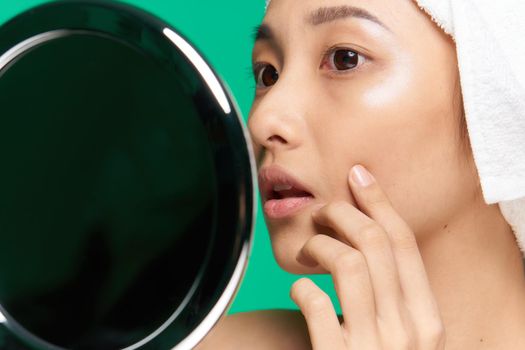woman of asian appearance towel on head clean skin touching face mirror with hands. High quality photo