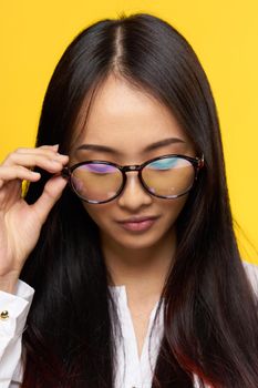 asian woman with glasses student close-up yellow background. High quality photo