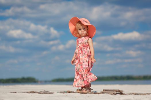 A little girl in a beautiful sarafna plays in the sand on the beach.