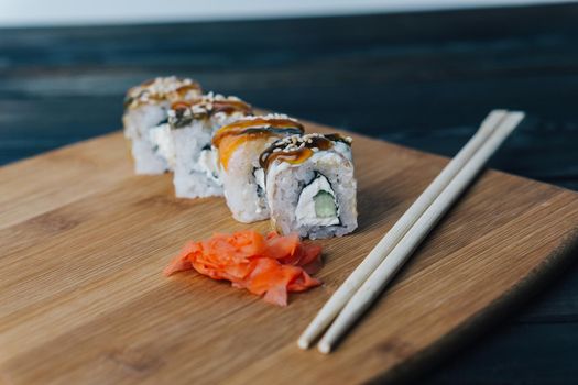 sushi rolls red ginger chopsticks wood board close-up. High quality photo