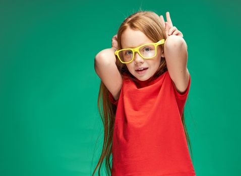 cute girl with red hair yellow glasses emotions studio Green background. High quality photo