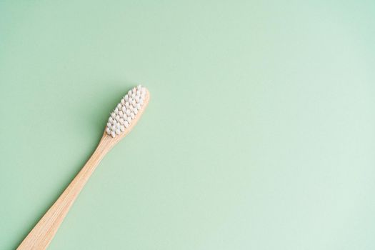 Eco friendly dental health antibacterial bamboo wood toothbrush on green background.