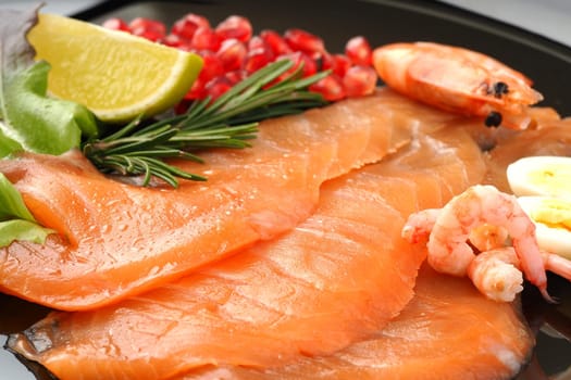 Red fish. Seafood dish, salted salmon shrimp on a flat plate with lemon and rosemary. High quality photo