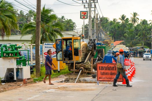 Workers removed a layer of asphalt from the road to lay pipes. Repair construction work on the street of the island in Thailand.
