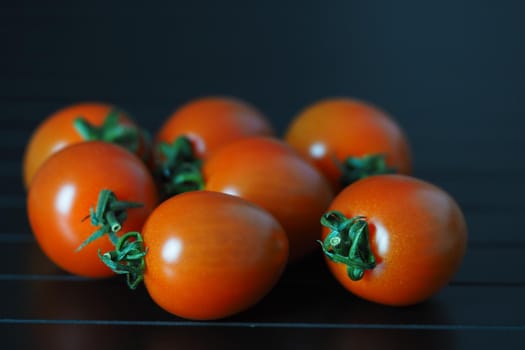 Red ripe cherry tomatoes on a black background close-up. High quality photo