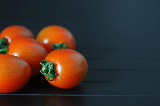 Red ripe cherry tomatoes on a black background close-up. High quality photo