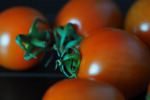 Red ripe cherry tomatoes on a black background close-up. High quality photo