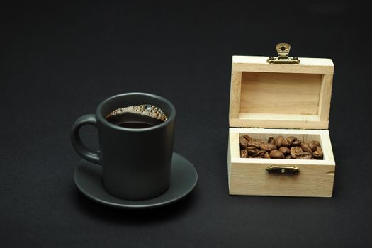 A cup of black coffee and coffee grain in a beautiful box. Black background. Close-up. High quality photo