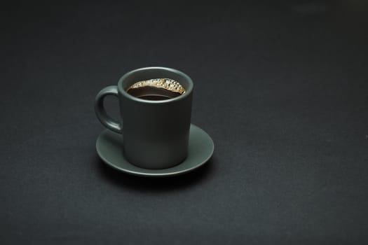 Coffee cup with a grey saucer on a black background. Isolated. Close-up.